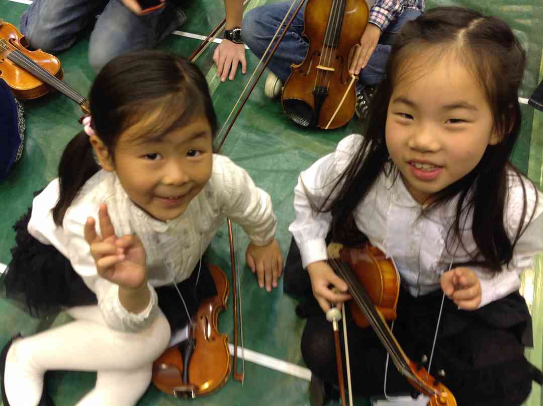 Two little girls from Taiwan waiting to have their instruments tuned at the Opening Ceremonies
