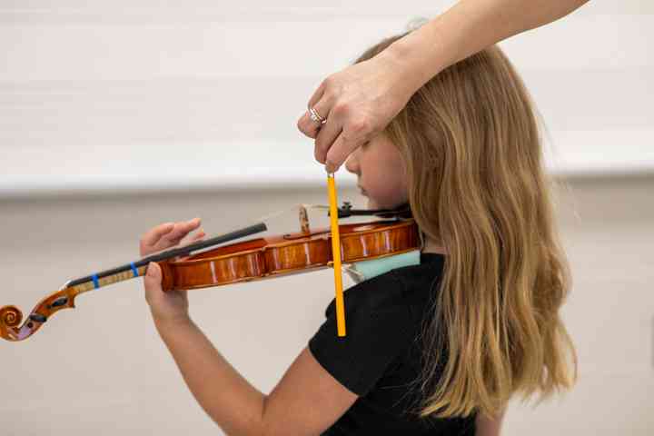 Figure 5. The corner of the violin aligns with the end of the student’s shoulder, as indicated by the pencil.